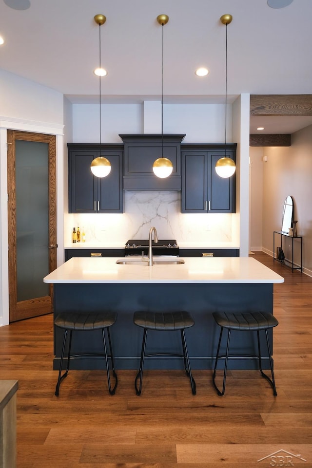 kitchen with dark hardwood / wood-style flooring, backsplash, and a kitchen island with sink