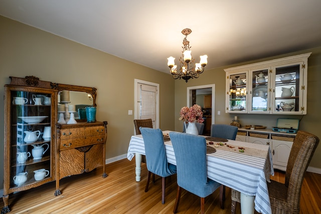 dining space with light hardwood / wood-style floors and a notable chandelier