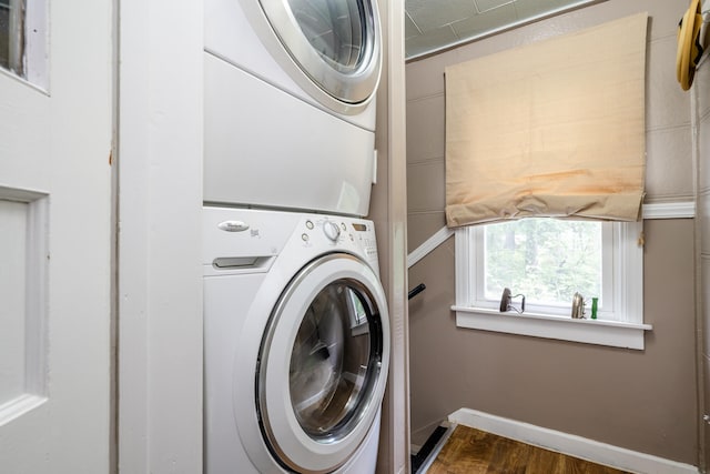 clothes washing area with dark hardwood / wood-style flooring and stacked washer and clothes dryer