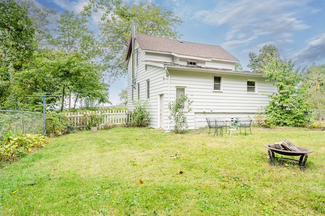 rear view of house featuring a lawn and an outdoor fire pit