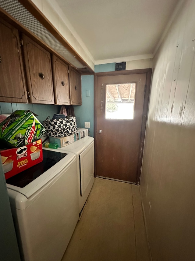 clothes washing area with cabinets and washing machine and clothes dryer