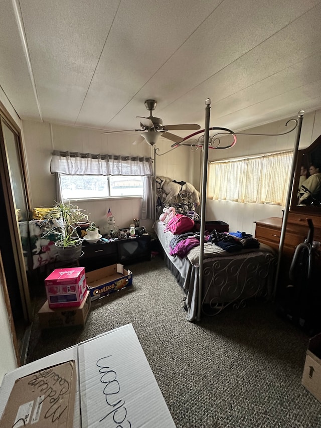 bedroom featuring ceiling fan, dark carpet, and a textured ceiling