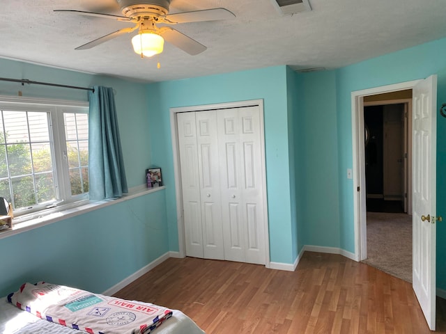 bedroom with hardwood / wood-style floors, a textured ceiling, a closet, and ceiling fan