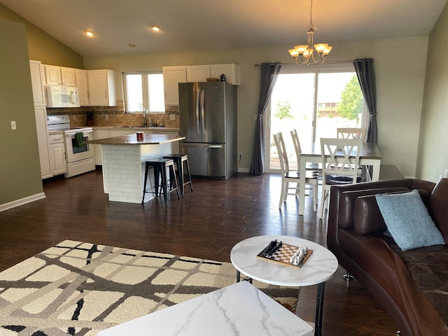 kitchen with pendant lighting, white appliances, dark hardwood / wood-style floors, and a kitchen island