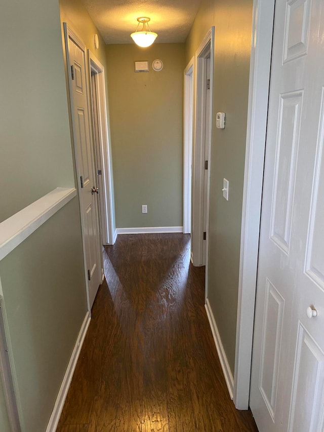 hallway featuring a textured ceiling and dark hardwood / wood-style flooring