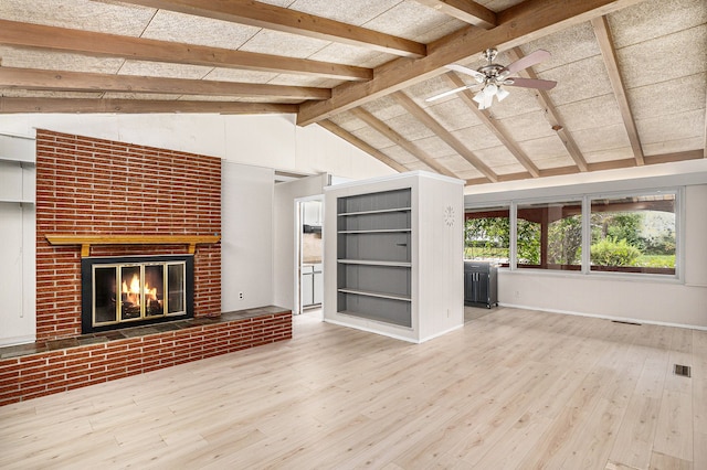 unfurnished living room with a fireplace, wood-type flooring, lofted ceiling with beams, and ceiling fan