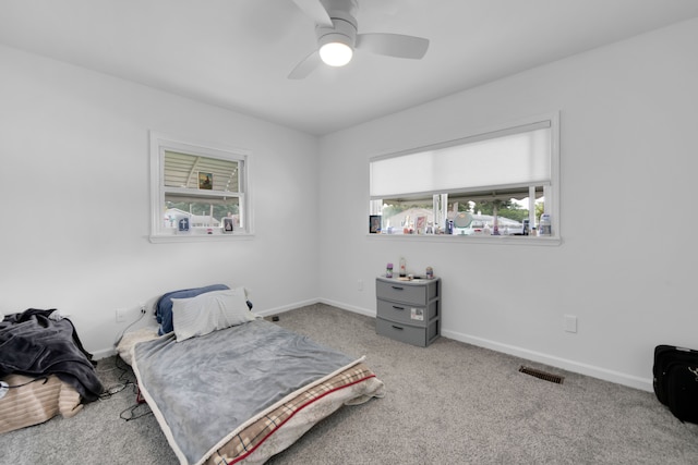 bedroom with multiple windows, light colored carpet, and ceiling fan