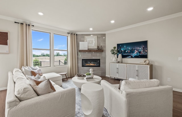 living room featuring a tiled fireplace, dark hardwood / wood-style flooring, and crown molding