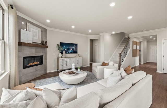 living room with dark hardwood / wood-style flooring, ornamental molding, and a tiled fireplace