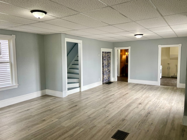 interior space with a drop ceiling and wood-type flooring