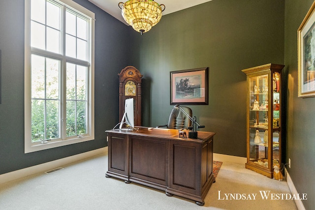 carpeted home office with a healthy amount of sunlight and a notable chandelier