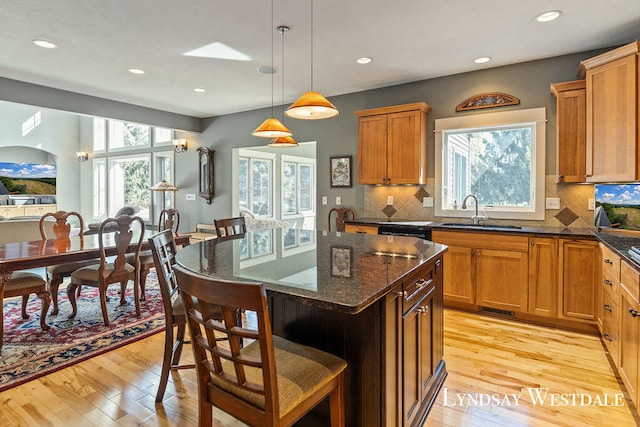 kitchen featuring light wood-type flooring, a breakfast bar, sink, pendant lighting, and a kitchen island