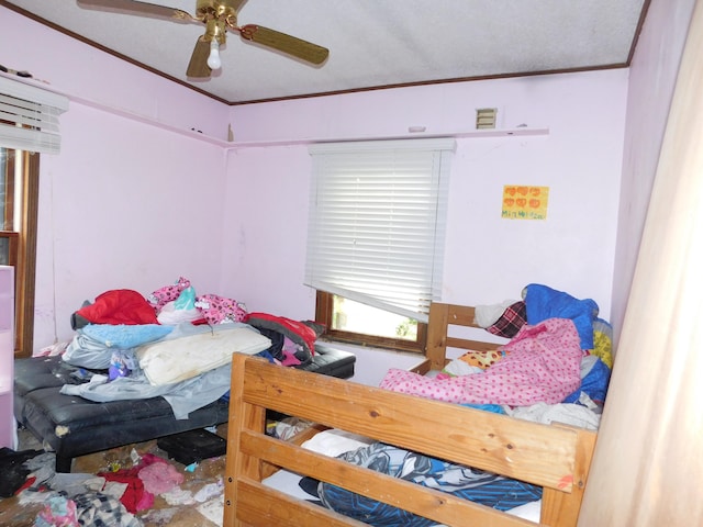 bedroom featuring ceiling fan, ornamental molding, and a textured ceiling