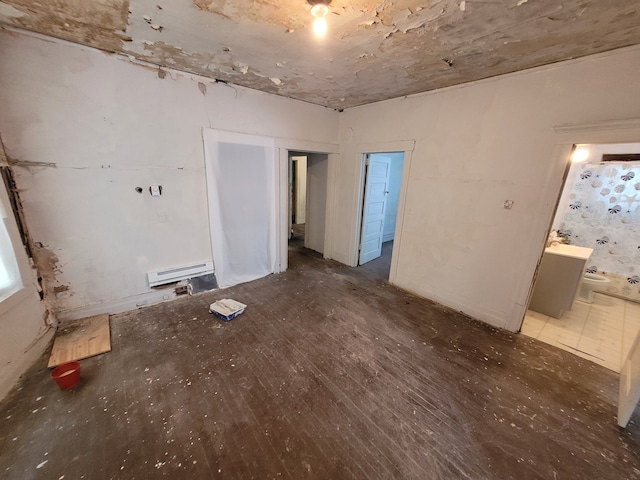 empty room with dark wood-type flooring and a baseboard heating unit