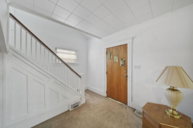 carpeted foyer entrance with crown molding