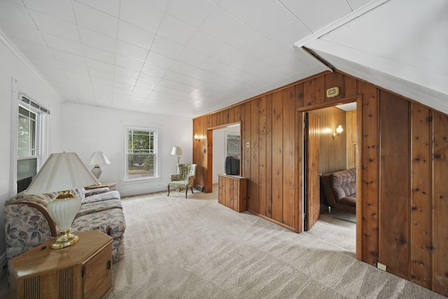 carpeted living room with wood walls, lofted ceiling, and ornamental molding