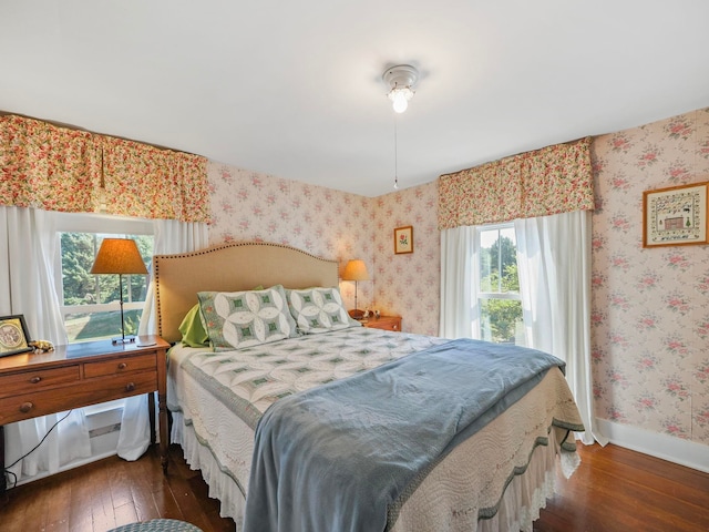 bedroom with dark hardwood / wood-style flooring and multiple windows