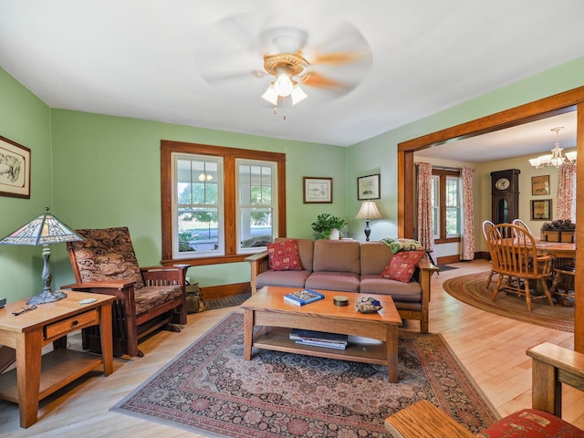 living room featuring ceiling fan with notable chandelier, light wood-type flooring, and a healthy amount of sunlight