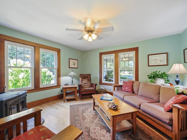 living room featuring ceiling fan, light wood-type flooring, and a wood stove