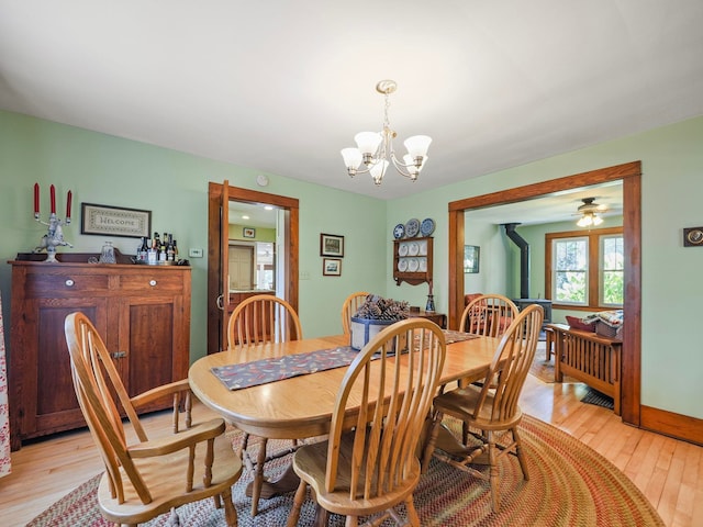 dining area with light hardwood / wood-style floors and ceiling fan with notable chandelier