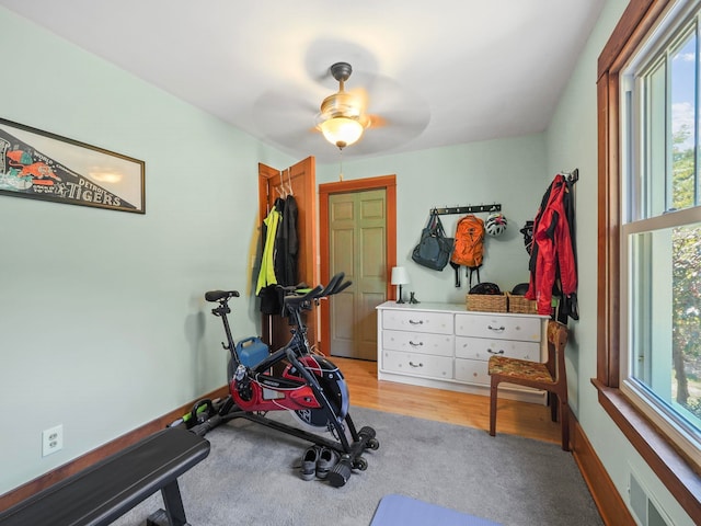 workout area with light hardwood / wood-style flooring and ceiling fan