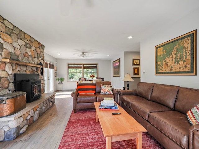 living room with hardwood / wood-style floors, ceiling fan, and a wood stove