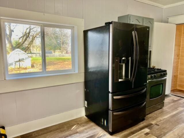 kitchen featuring black fridge with ice dispenser, stainless steel range with gas cooktop, green cabinetry, and wood-type flooring