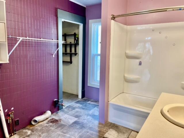 bathroom with vanity, tile walls, and tiled shower / bath