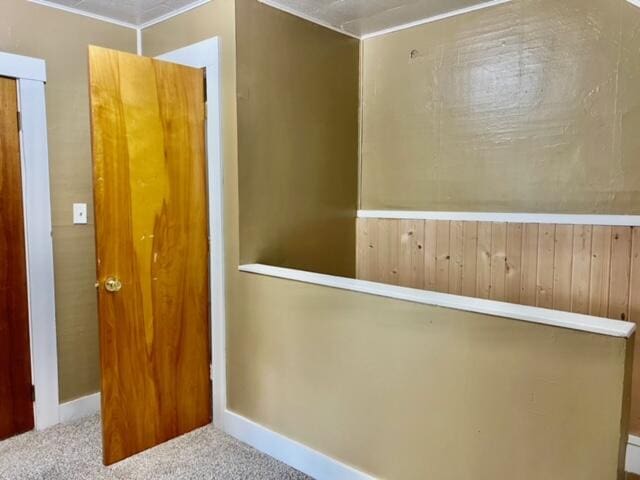 hallway with carpet floors and wood walls