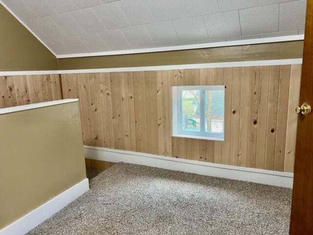 additional living space with wood walls, carpet floors, and vaulted ceiling