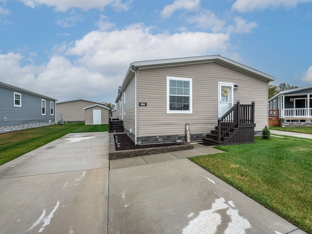 manufactured / mobile home featuring a front lawn and an outdoor structure