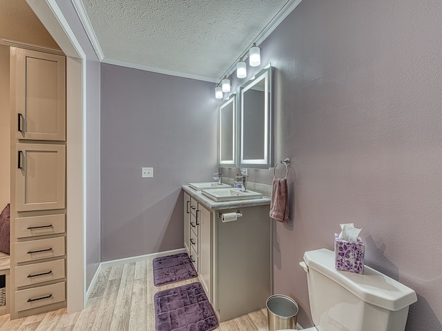 bathroom with a textured ceiling, vanity, wood-type flooring, and crown molding