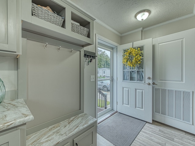 mudroom with light wood-type flooring, a textured ceiling, and ornamental molding