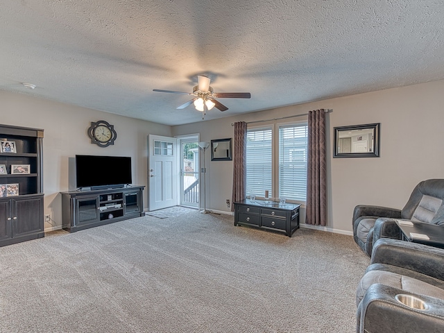 living room featuring ceiling fan, carpet floors, and a textured ceiling