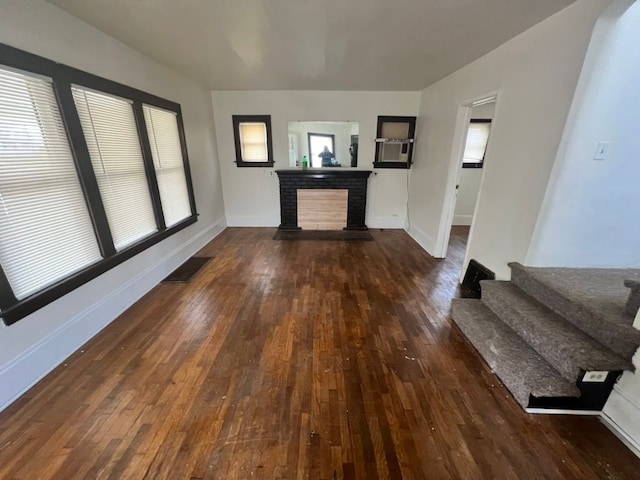 unfurnished living room with a brick fireplace and dark wood-type flooring