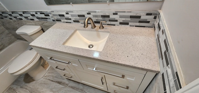 bathroom with vanity, toilet, a tub to relax in, and tasteful backsplash