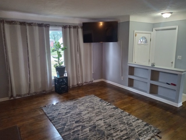 unfurnished living room featuring a textured ceiling and dark wood-type flooring