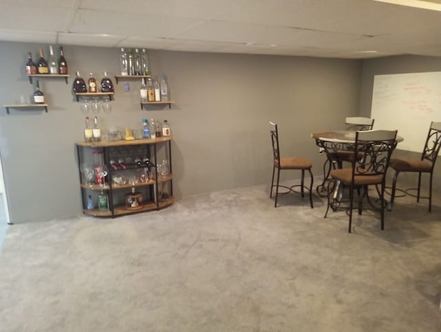 carpeted dining room with a paneled ceiling and indoor bar