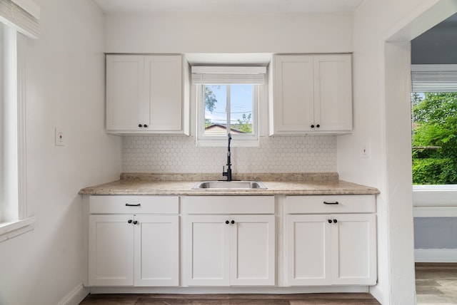 kitchen with white cabinets, backsplash, hardwood / wood-style flooring, and sink