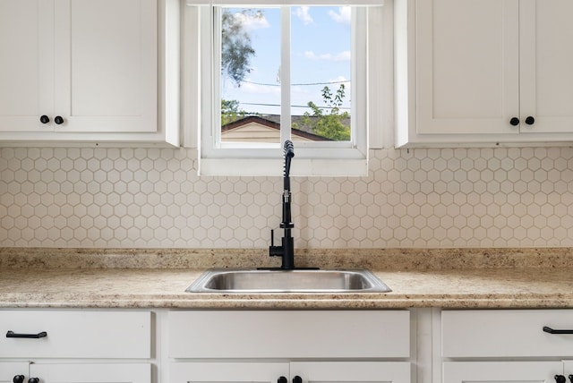 kitchen with tasteful backsplash, white cabinetry, and sink