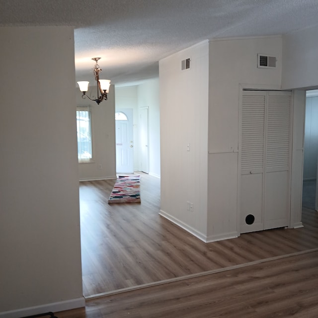 unfurnished room with a chandelier, wood-type flooring, and a textured ceiling