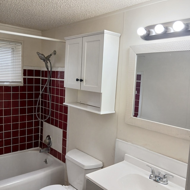 full bathroom with a textured ceiling, vanity, toilet, and tiled shower / bath