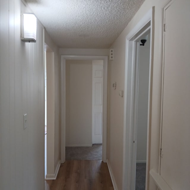 corridor featuring dark hardwood / wood-style flooring and a textured ceiling