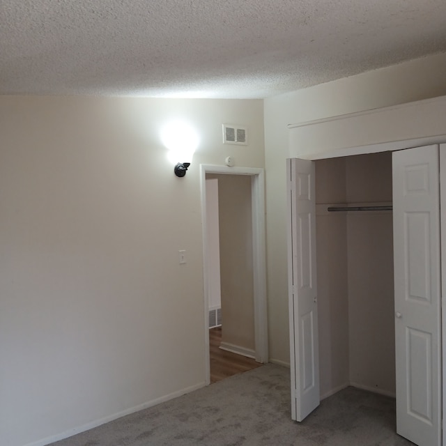 unfurnished bedroom with carpet flooring, a textured ceiling, and a closet