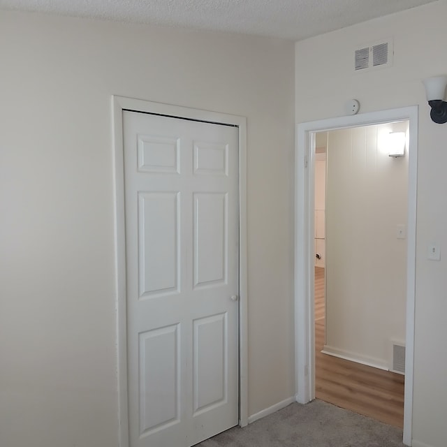 unfurnished bedroom featuring a textured ceiling, light hardwood / wood-style flooring, and a closet