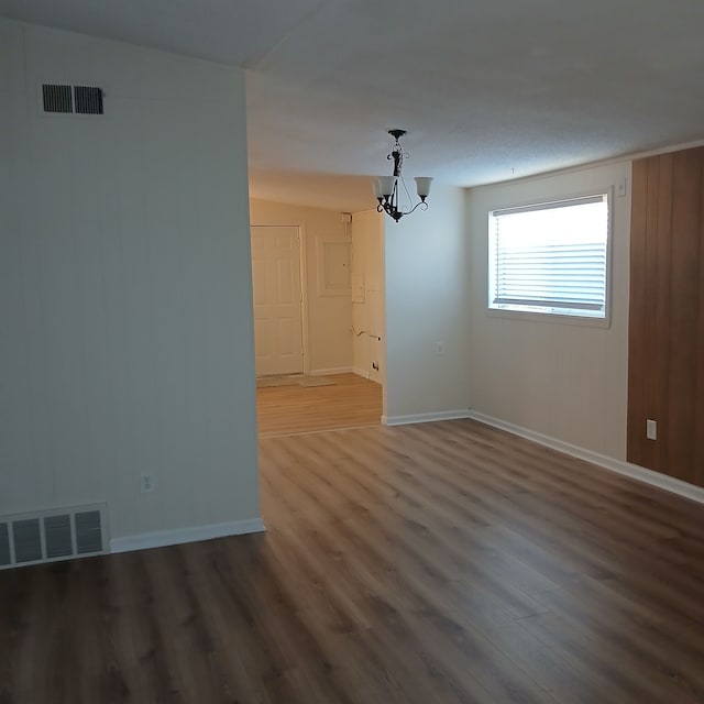 spare room with a chandelier, hardwood / wood-style floors, and vaulted ceiling