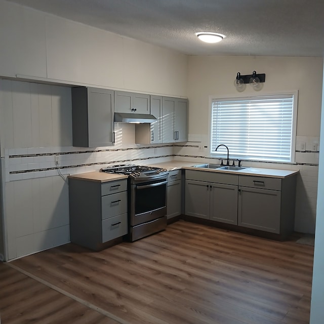 kitchen with sink, stainless steel gas range oven, dark hardwood / wood-style floors, a textured ceiling, and gray cabinets