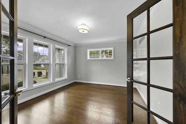 spare room featuring plenty of natural light, dark hardwood / wood-style floors, crown molding, and french doors