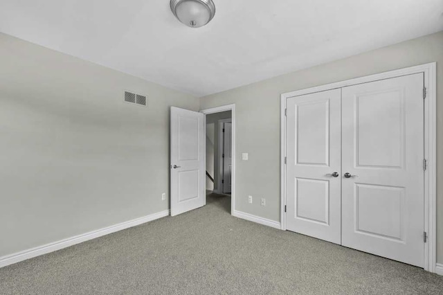 unfurnished bedroom with light colored carpet and a closet