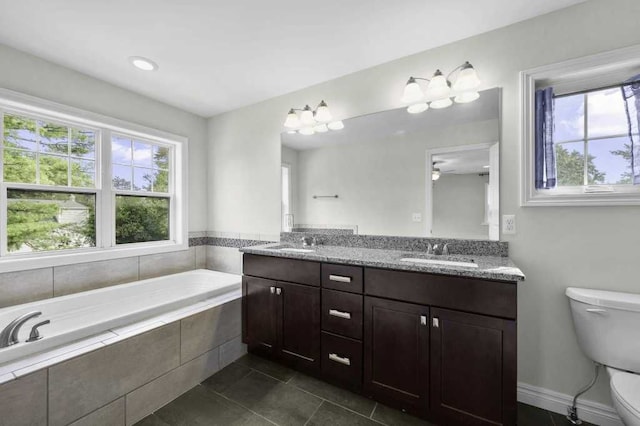 bathroom with ceiling fan, a relaxing tiled tub, tile patterned floors, toilet, and vanity